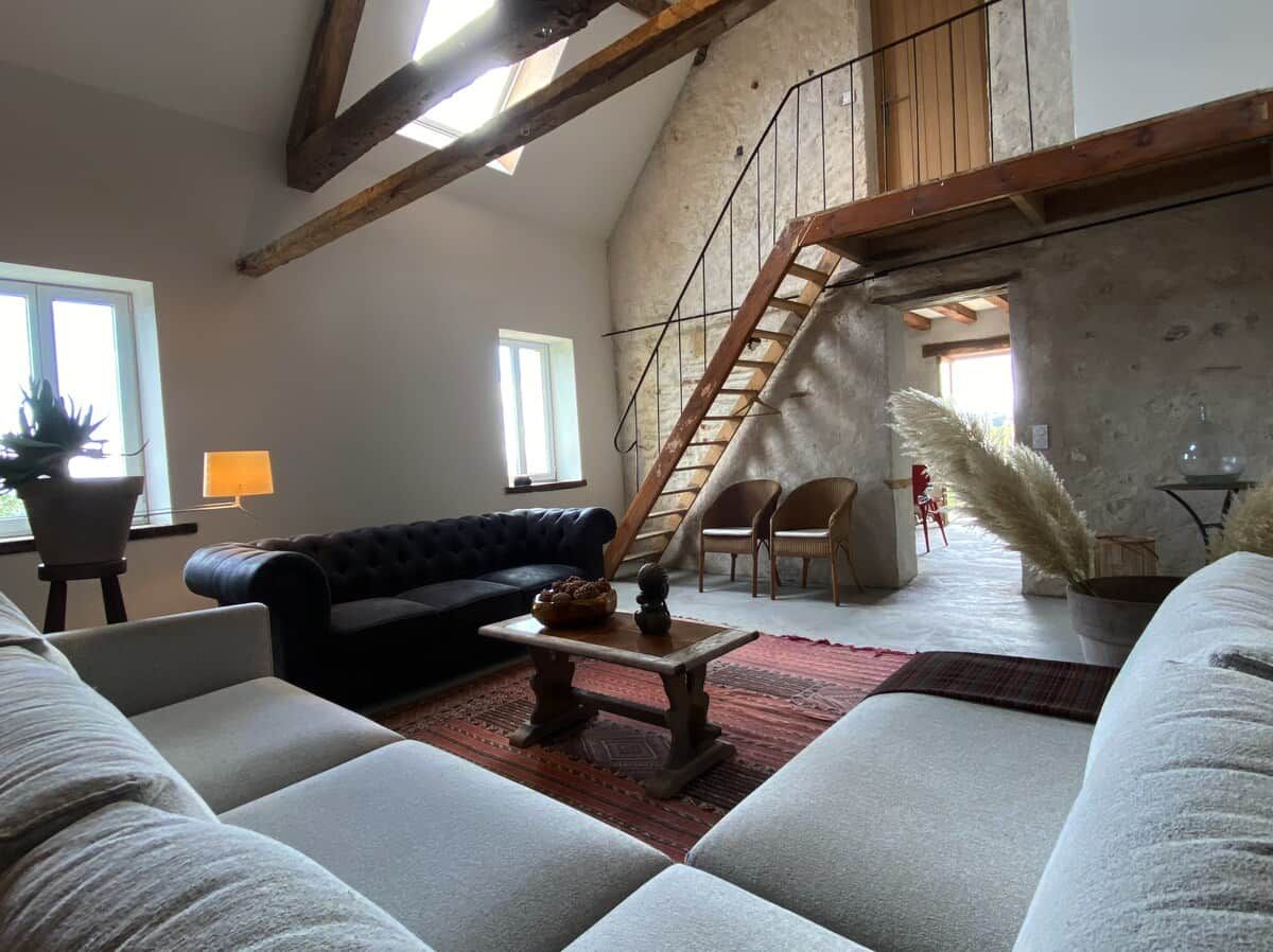 Un vaste espace de vie doté d’un haut plafond, d’un escalier et offrant une vue sur l’extérieur.
