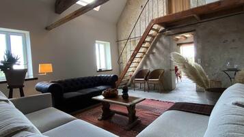 Un vaste espace de vie doté d’un haut plafond, d’un escalier et offrant une vue sur l’extérieur.