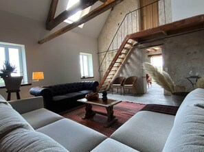 Ein großzügiger Wohnbereich mit hohen Decken, einer Treppe und Blick ins Freie.