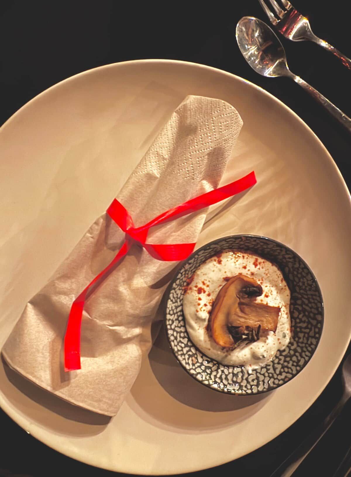 Une assiette avec un objet emballé et un petit bol contenant de la nourriture.