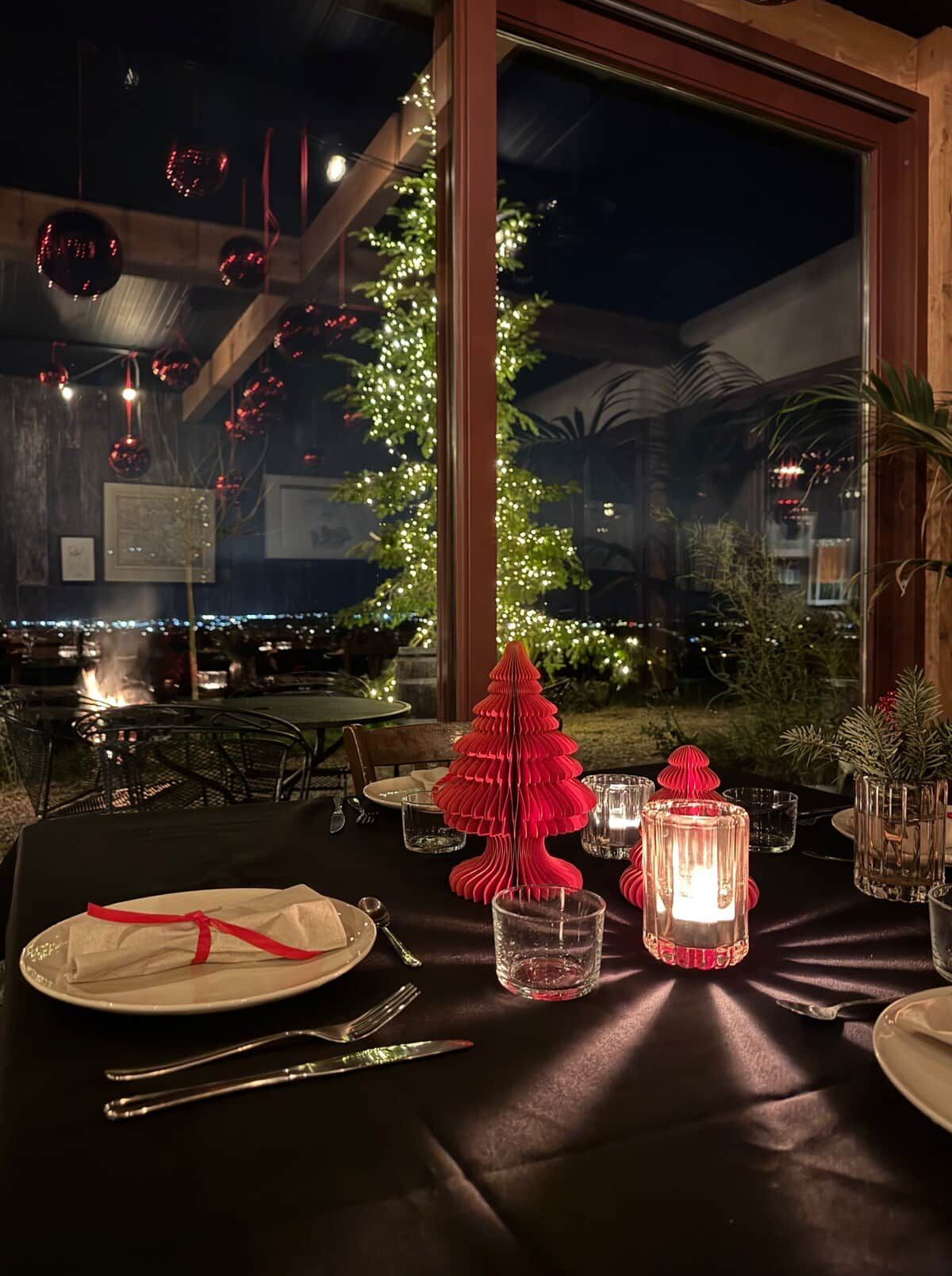 Mesa lista para comer con vista a un árbol de Navidad.