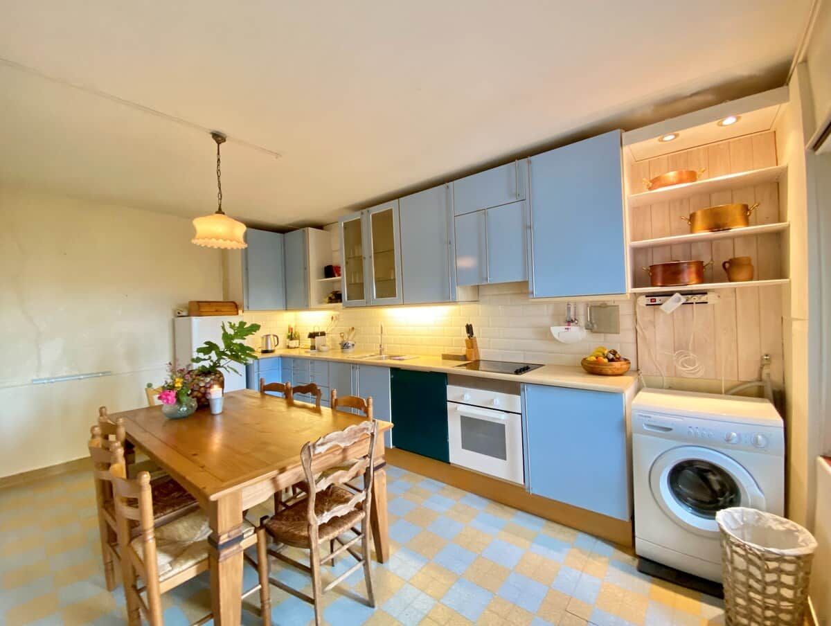 Une cuisine compacte comprenant une table à manger, des chaises, un lave-linge et un évier.