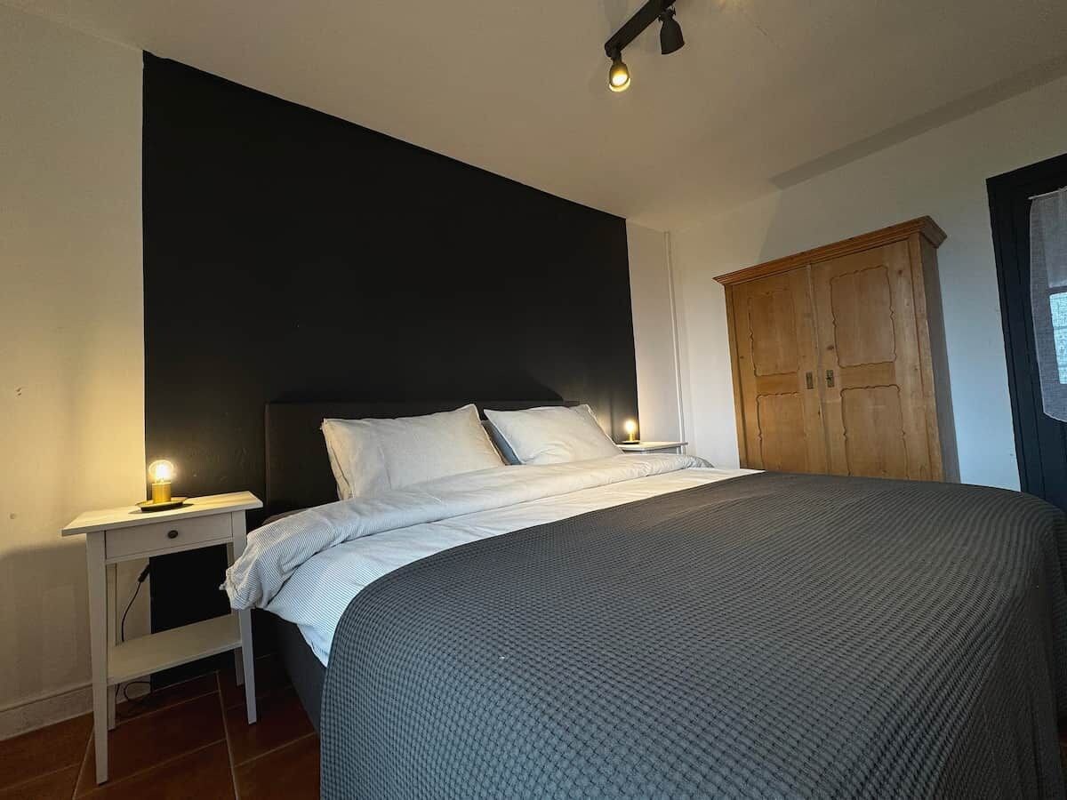 Une chambre à coucher comprenant un lit, des lampes de chevet, une armoire et un luminaire fixé au mur.