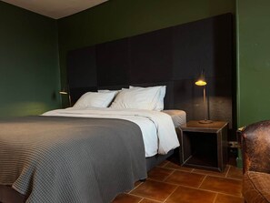 Une chambre à coucher avec un lit, une table de chevet, une lampe et une chaise.