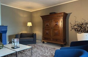 Una sala de estar con sofá, aparador, lámpara y una planta decorativa.