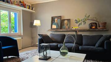 En stue med sofa, sofabord og lampe. Reoler og et vindue med udsigt.
