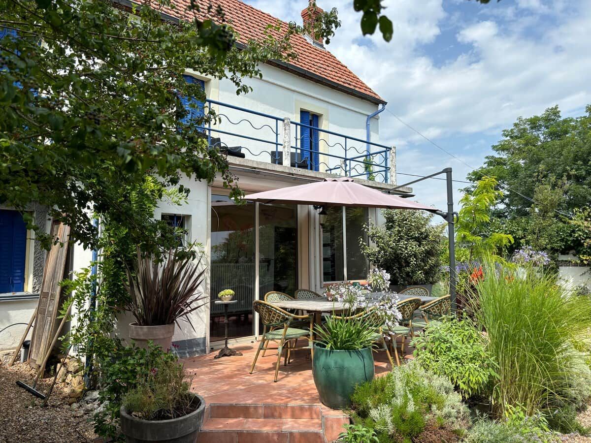 Una casa con patio, mobiliario exterior y plantas en macetas.