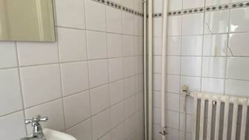 Une salle de bain avec un lavabo blanc, des toilettes et un espace douche.