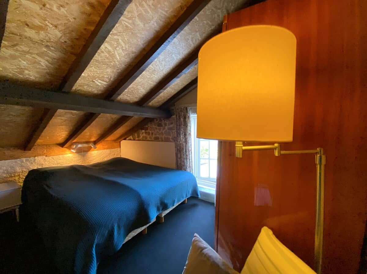 Une chambre à coucher avec un lit, une lampe et une fenêtre.