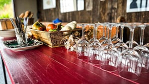 Una mesa de comedor con copas de vino, platos y una cesta de verduras.