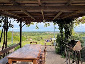 An outdoor dining area with a table and chairs, a barbecue grill, and a view of the countryside. - Cozy duplex gite with a shared pool in Digoin (Digoin)