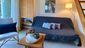 Una sala acogedora con un sofá, una mesa de madera con un florero y una lámpara.