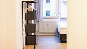 Una habitación con cama, un radiador y un perchero.