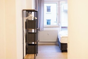 Une pièce avec un lit, un radiateur et un portant à vêtements.