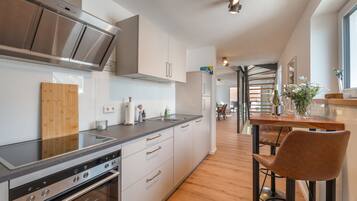 Een moderne keuken met roestvrijstalen apparatuur, houten vloeren en een bar met krukken.