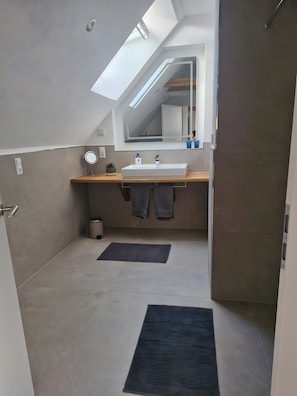 Ein modernes Badezimmer mit Oberlicht, Waschbecken, Spiegel und Handtuchhalter.