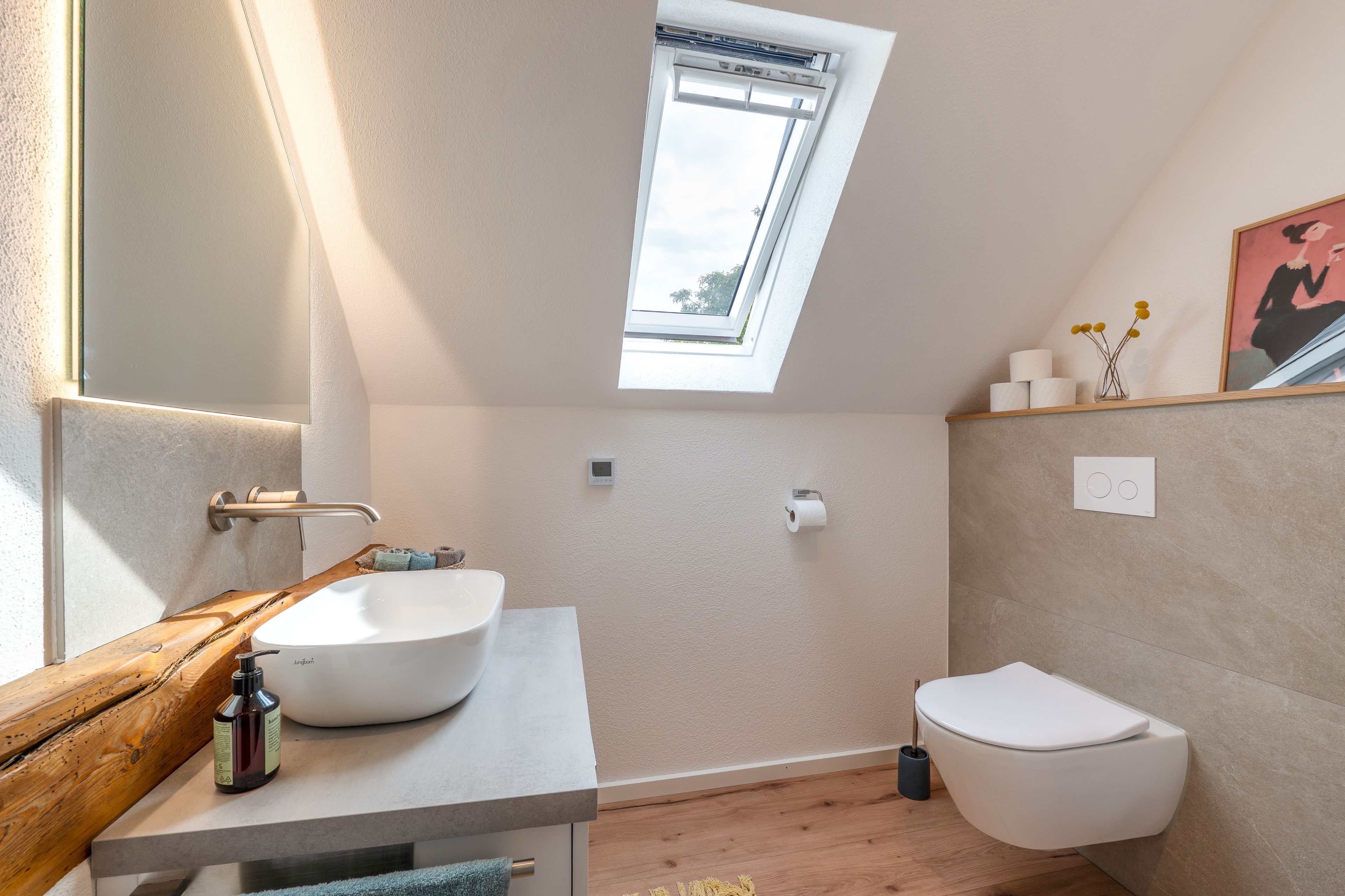 Ein modernes Badezimmer mit Oberlicht, einem Holzkosmetikschrank, einer Toilette und einem kleinen Ablagefach für Pflegeprodukte.