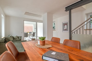 Un salon moderne avec une table à manger en bois, des fauteuils en cuir, un canapé vert et une plante en pot.