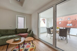 Un salon moderne avec un canapé vert, une petite table ronde et un tapis coloré.