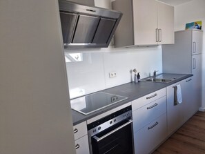 A modern kitchen with stainless steel appliances, white cabinetry, and a black countertop.
