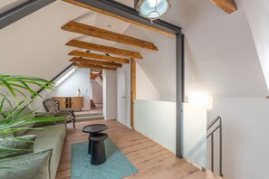 Un interior modern amb bigues de fusta, una escala, un sofà i una zona de menjador.