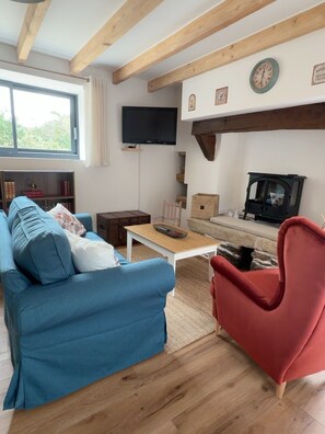 Ein Wohnzimmer mit einem blauen Sofa, einem roten Sessel, einem Fernseher, einem Kamin und einer Steinwand.