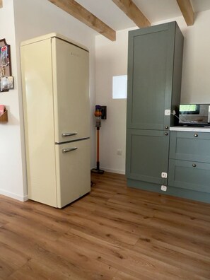 Eine Küche mit einem alten Kühlschrank, einem Schrank und einer Stehlampe.