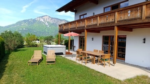 A chalet with a balcony, a hot tub, and a dining area with outdoor seating. - Vrbo Property (Unterwössen)