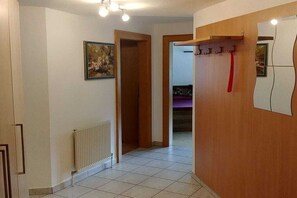 A hallway with a radiator, a door leading to another room, and a coat rack with a red item. - Holiday apartment in Vomp with swimming pool (Vomp)