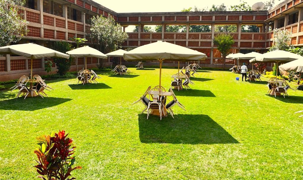Un patio exterior con varias mesas y sillas, rodeado por un edificio de fachada de ladrillo.