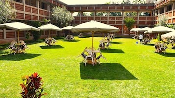 Un patio exterior con varias mesas y sillas, rodeado por un edificio de fachada de ladrillo.