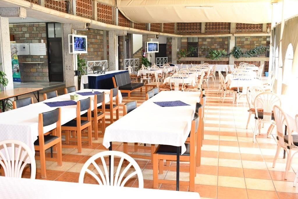 Un restaurante con varias mesas y sillas, una barra y una pantalla de televisión.