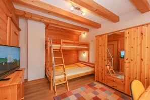 L’intérieur d’une cabane en bois, avec un lit superposé, un bureau doté d’une télévision et un tapis aux couleurs vives.