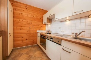 Eine Küche mit Holzwandverkleidung, weißen Schränken, einem Einbauofen und einem Spülbecken.