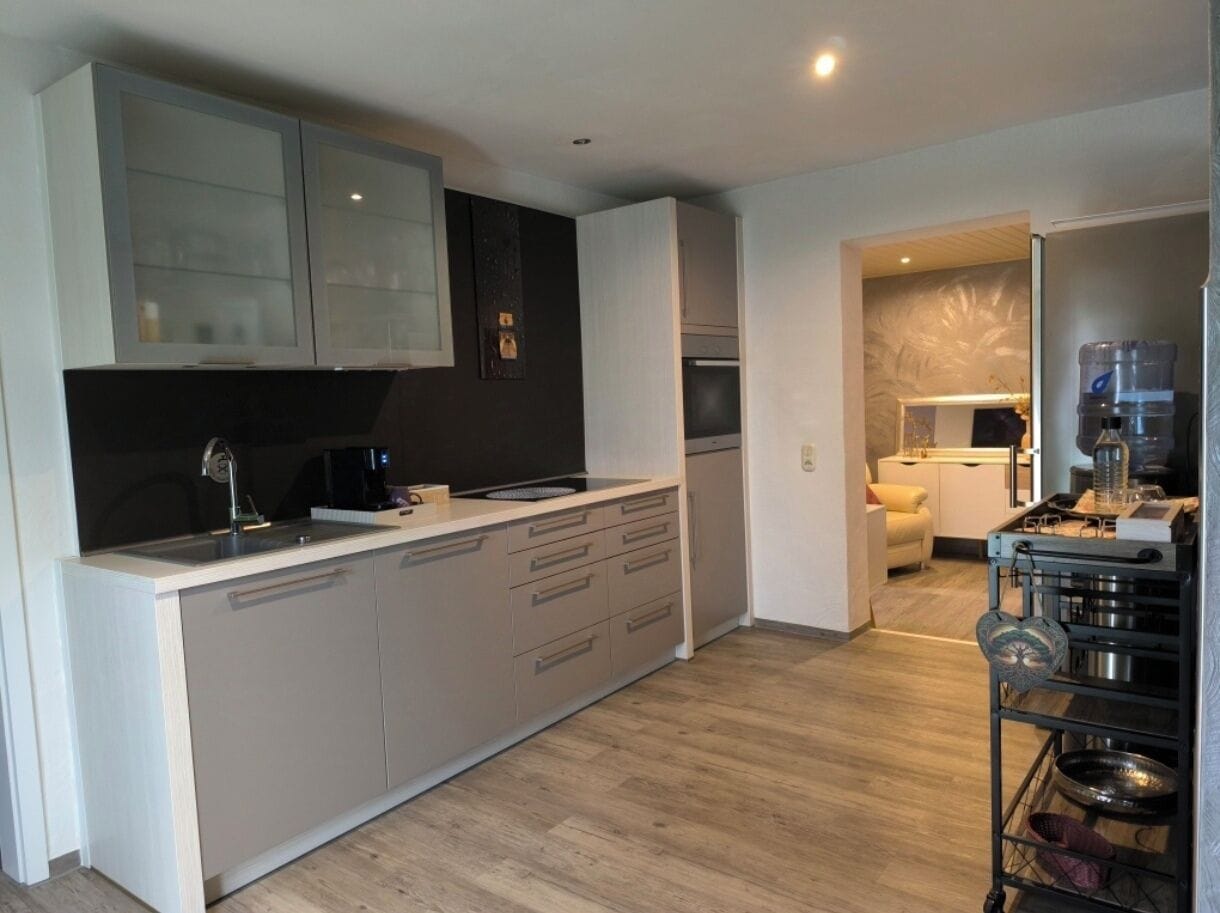 A modern kitchen with a central island, built-in appliances, and a dining area with a sofa.