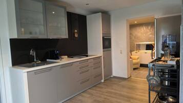 A modern kitchen with a central island, built-in appliances, and a dining area with a sofa.