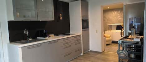 A modern kitchen with a central island, built-in appliances, and a dining area with a sofa.