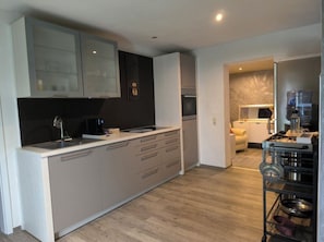 Una cucina moderna con isola centrale, elettrodomestici integrati e zona pranzo con divano.