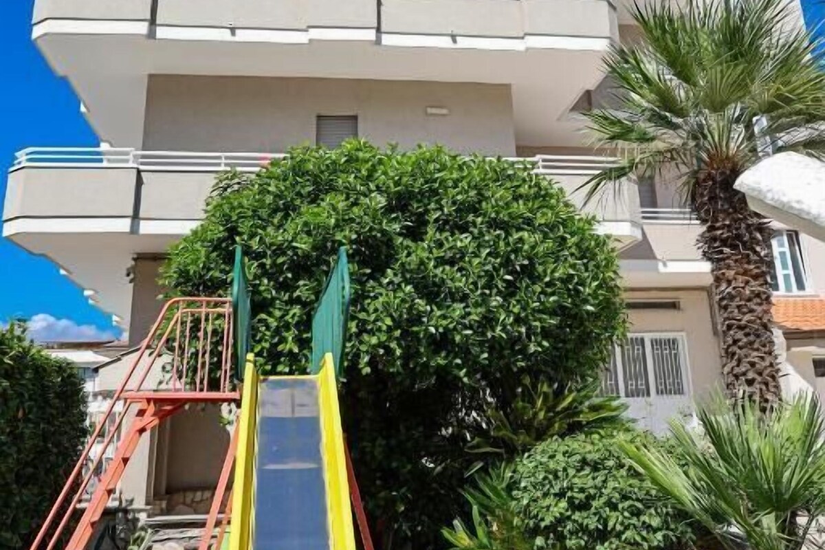 Un edificio a più piani con un'area giochi che include uno scivolo e delle scale.