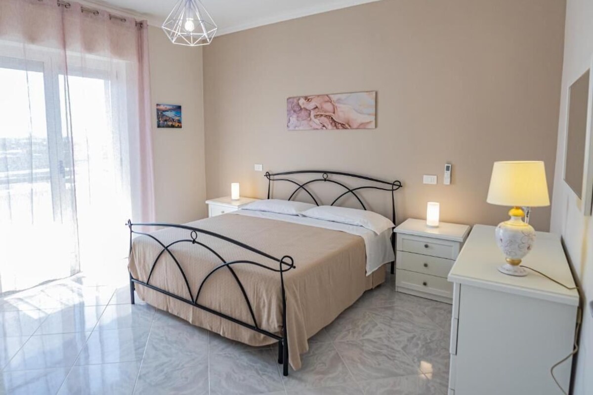 Una camera d'albergo con un letto, comodini, una lampada e opere d'arte appese al muro.