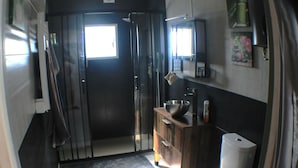 Casa de banho compacta com sanita, lavatório e janela pequena.