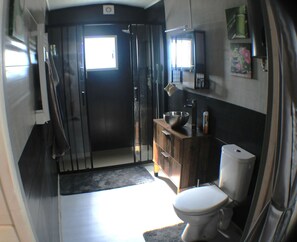 Een kleine badkamer met toilet, wastafel en een klein raam.