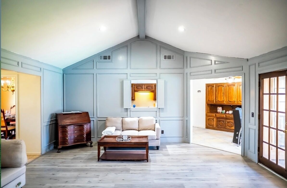 Un salon spacieux avec un plafond haut, un meuble en bois, un canapé et une table basse.