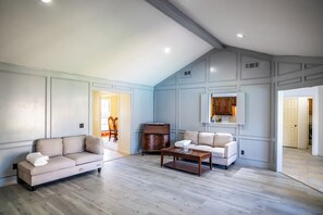 A spacious living room with a high ceiling, a wooden coffee table, a beige sofa, and a white armchair. - 4BR Carrollton Escape (Carrollton)