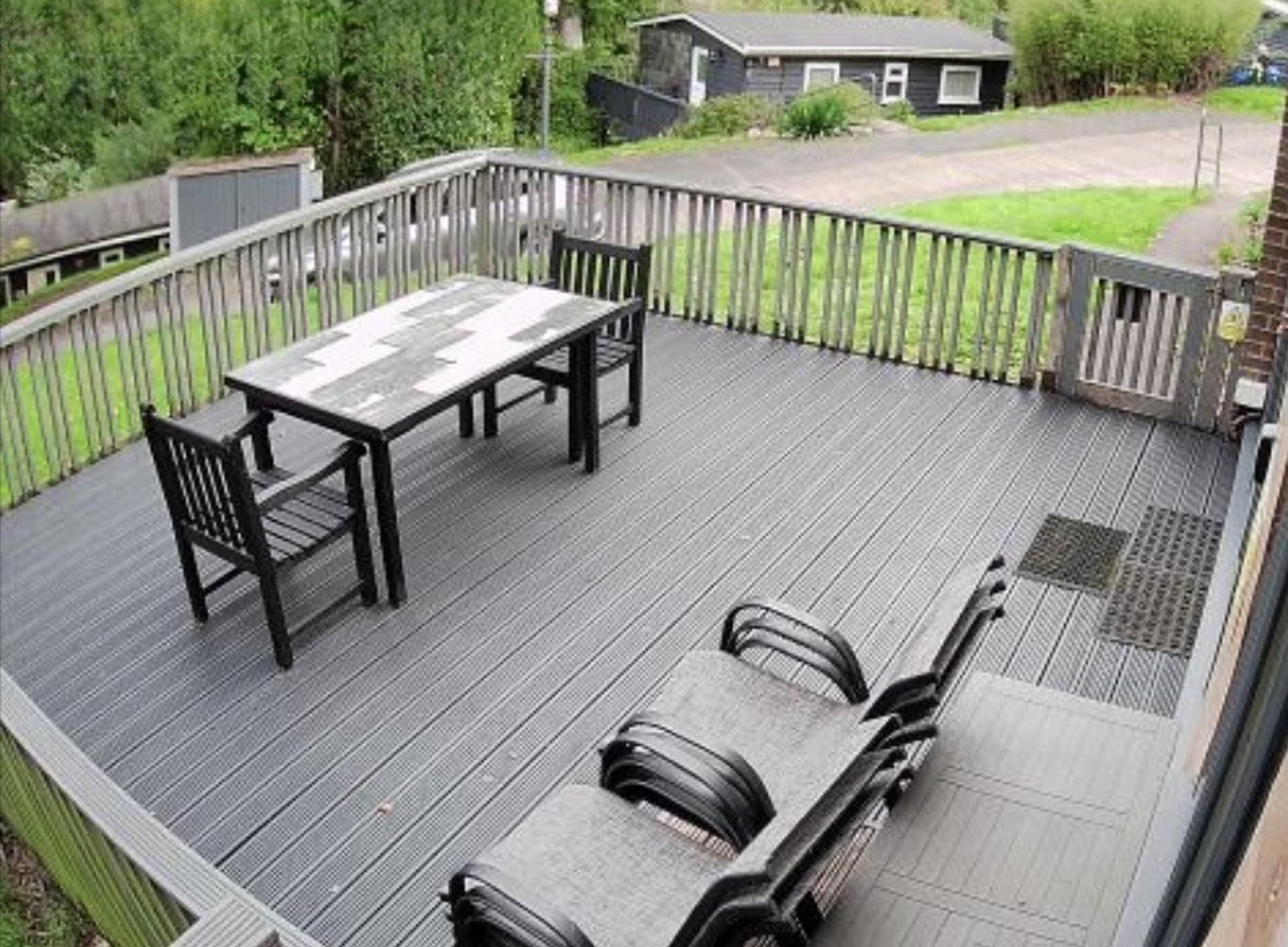 A deck with a table and chairs, surrounded by a wooden fence.