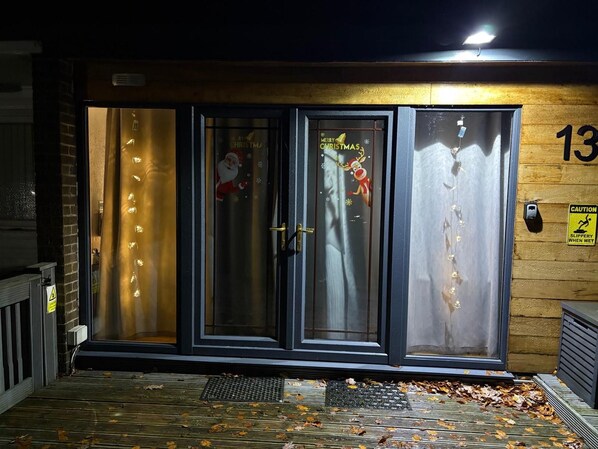 A building entrance with a glass door, a Christmas wreath, and a caution sign. - Pet Friendly 2-bed Lodge, Sleeps 5, Pool & Parking (Caernarfon)