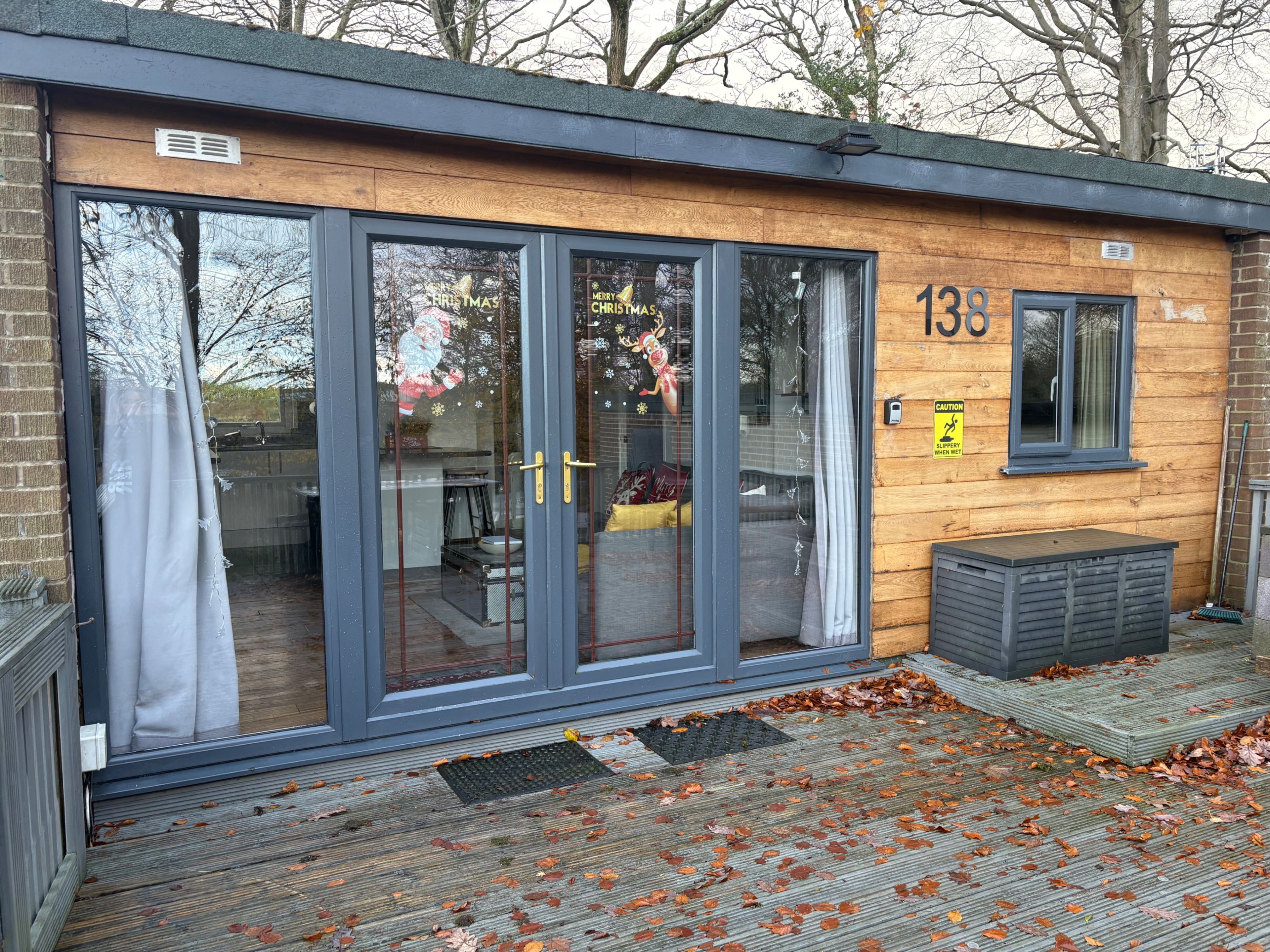 A modern building with large glass doors, a wooden exterior, and a number '138' on the wall.