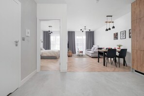 A modern apartment with a dining area, a sofa, a bed, and a kitchen visible through an open door. - Modern Apartment in the City Center | Balcony (Łódź)