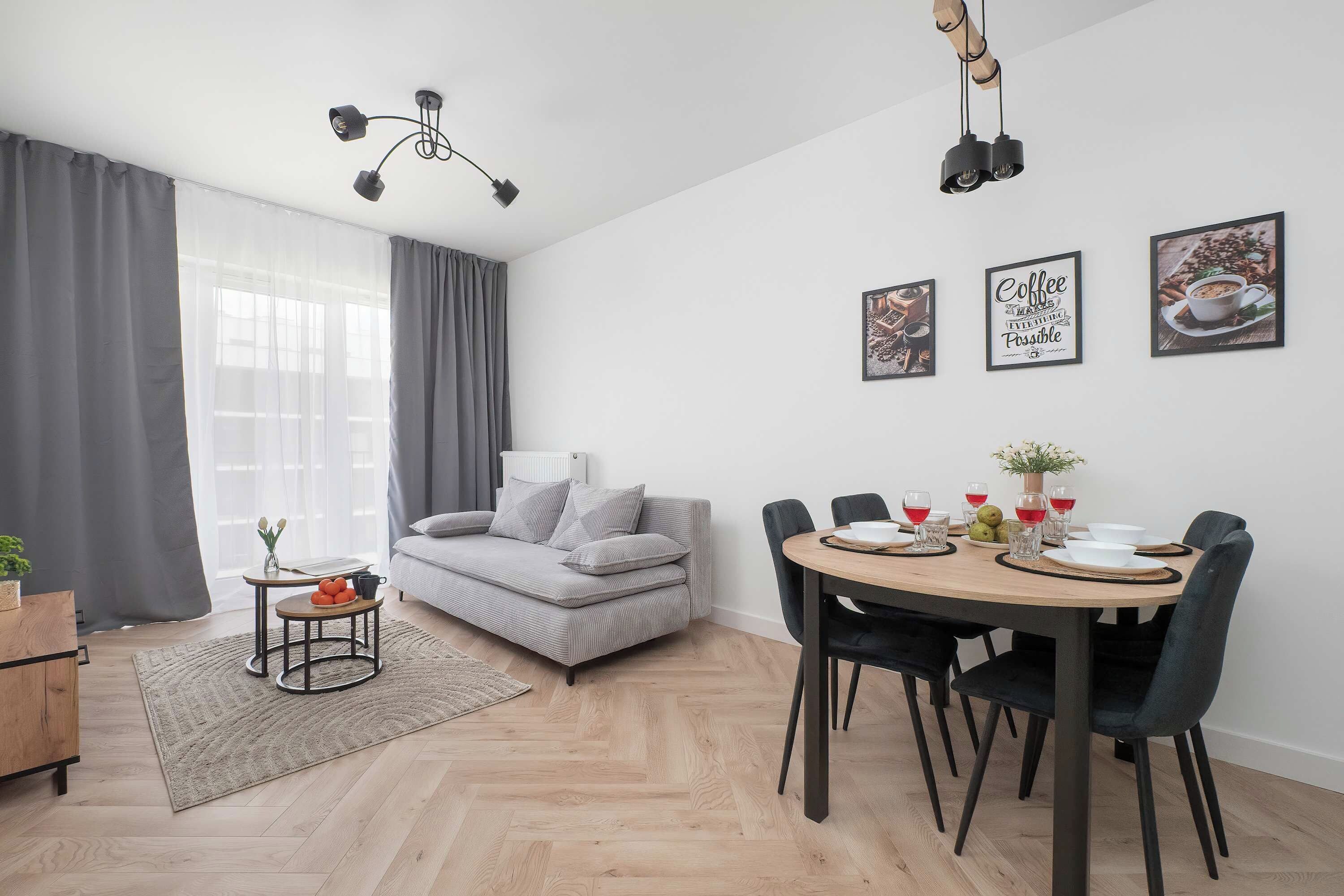 Una sala moderna con un sofá, una mesa de comedor para cuatro personas y una mesa de centro.