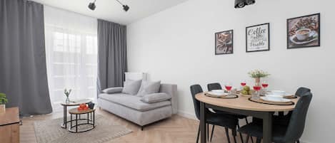 A modern living room with a sofa, a dining table set for four, and a coffee table.